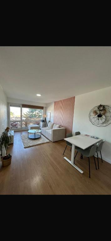 a living room with a table and a couch at Appartement moderne avec parking privé Lit connecté LED & rétroprojecteur 5 min Zénith in Saint-Herblain