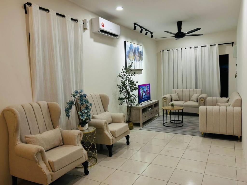a living room with couches chairs and a tv at Homestay D'Aina in Teluk Intan