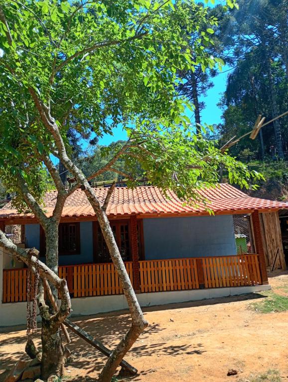 a house with a tree in front of it at Chalé vale do Monte Verde in Camanducaia
