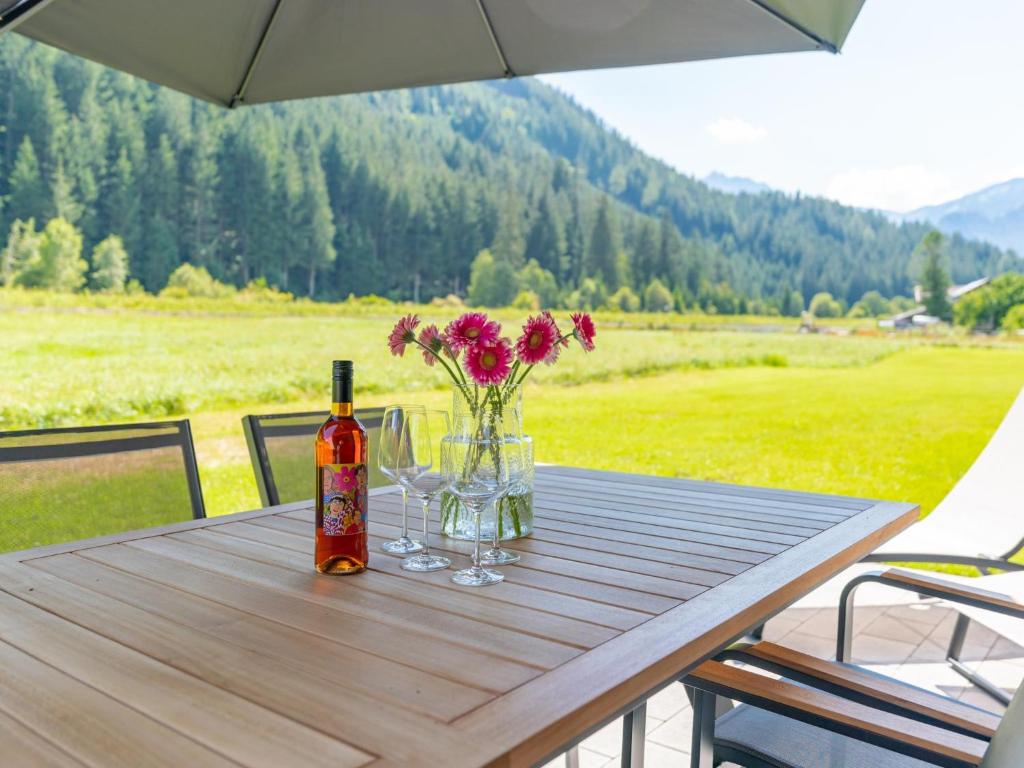 a table with a bottle of wine and flowers on it at Pinzgau Lodge 2E in Wald im Pinzgau