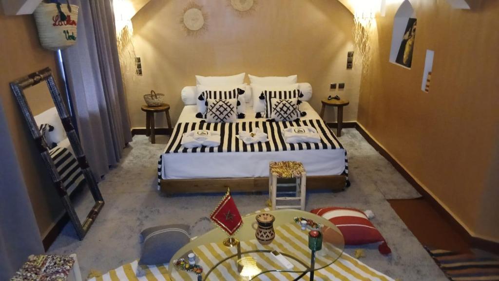 a bedroom with a large bed and a table at La Colline Verte Dar Ait El Abass in Ouarzazate