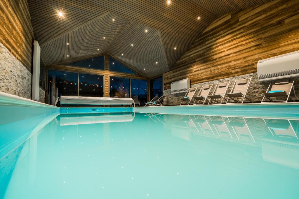 a swimming pool with chairs in a building at Gites des Gentianes in Morbier