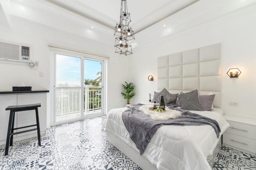 ein weißes Schlafzimmer mit einem Bett und einem Fenster in der Unterkunft Soderberg By J&J Homes At Amani Grand Resort Residences Near Airport in Mactan