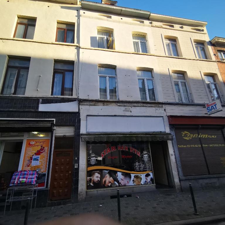 a tall white building with a sign in the window at Trapmouse hostel in Brussels