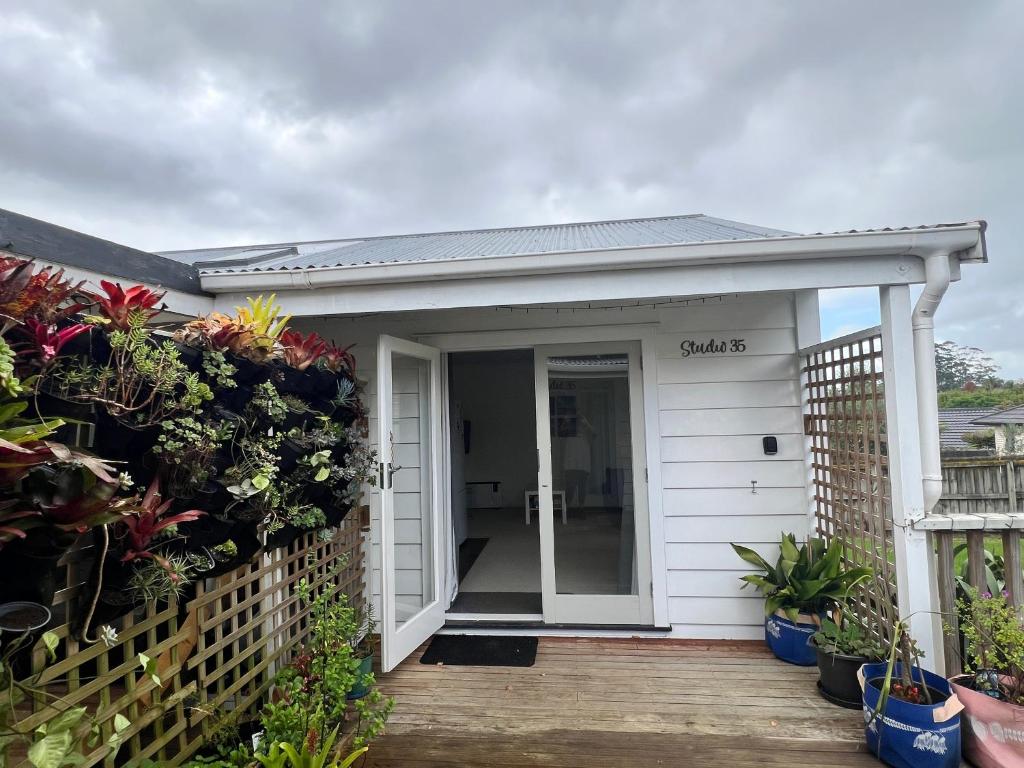 a white house with a porch with plants at Studio 35 Kerikeri in Kerikeri