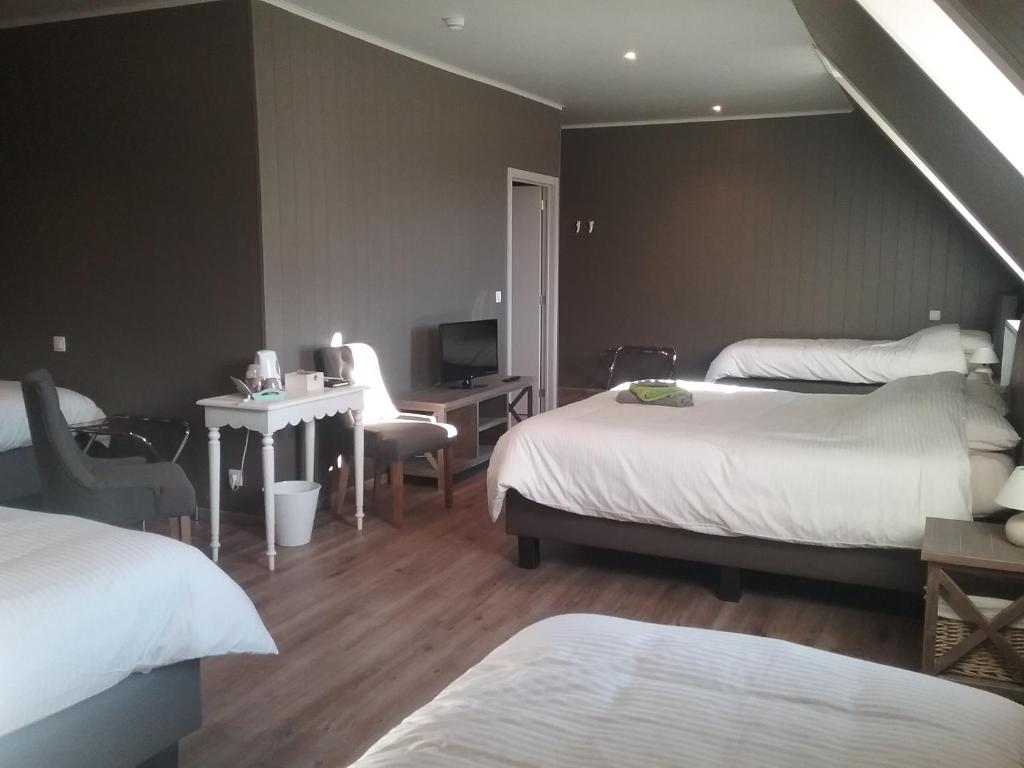 a bedroom with two beds and a desk and a television at B&B De Dulle Koe in Waregem