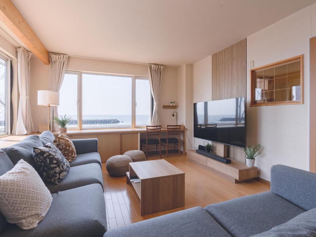 a living room with a couch and a flat screen tv at TOYA Station Villa in Lake Toya