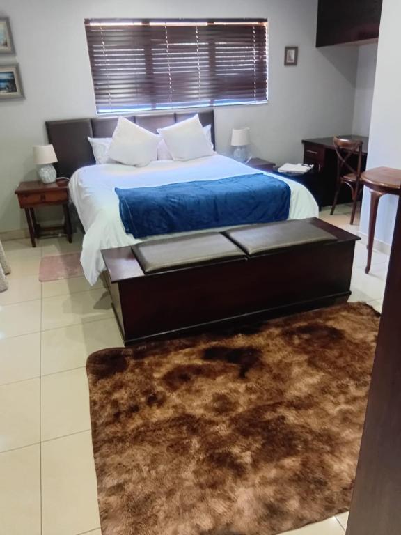 a bedroom with a bed with a blue blanket and a rug at UVongo Welcome House in Margate