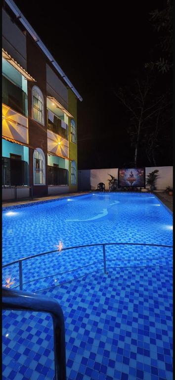 a large swimming pool in front of a building at night at Thilo Guest House Auroville in Auroville