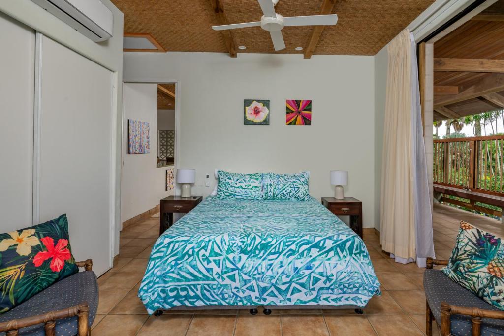 a bedroom with a bed and two chairs at Tipani Villa Sovereign Palms CI in Rarotonga