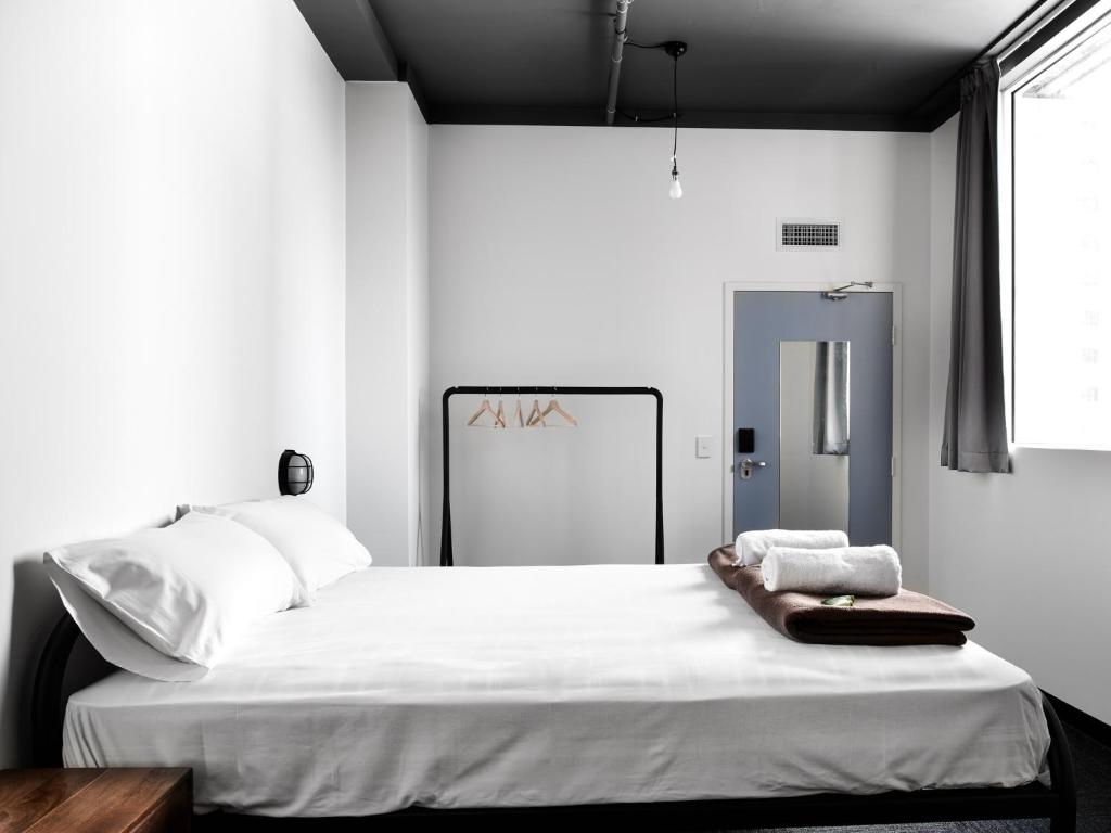 una camera da letto con un grande letto con lenzuola bianche di The Pod Sydney a Sydney