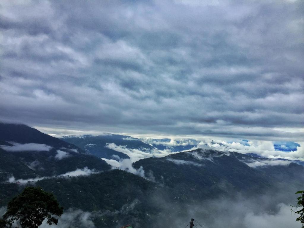 a view of a mountain valley with clouds in the sky at Dafey Homestay in Darjeeling