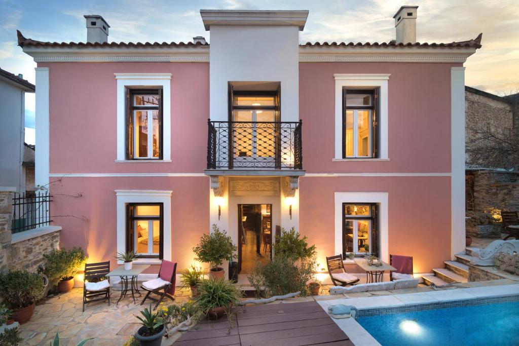 a pink house with a pool in front of it at Αρχοντικό Ταξίμι - Ανθέων Έμπνευση in Argalasti