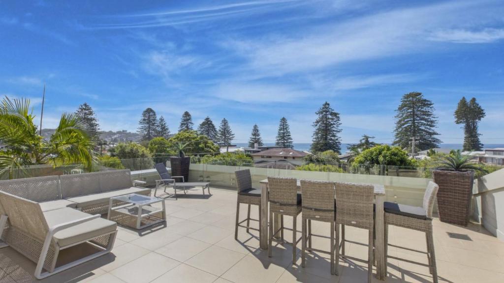 a patio with chairs and tables on a roof at Avoca Dream in Avoca Beach