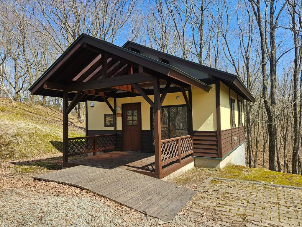 a small house with a porch and a roof at Katamaeyama Forest Park Cottage TypeC in Senboku