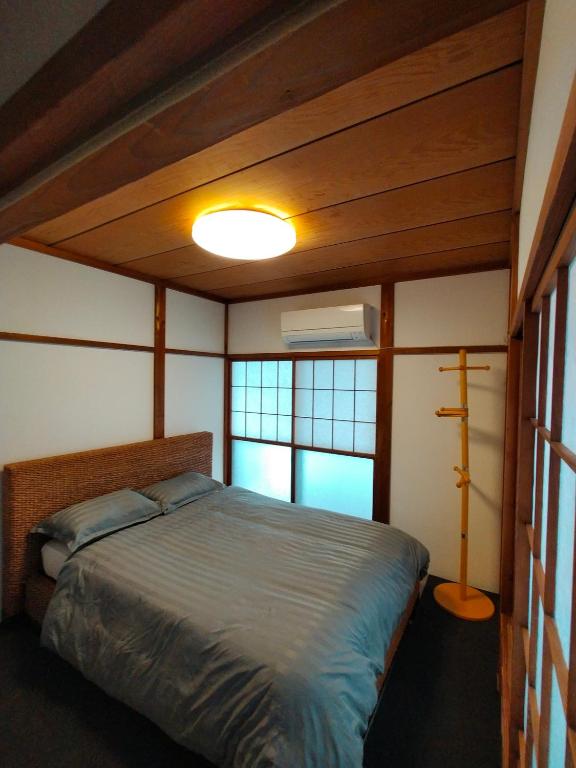 a bedroom with a bed and two windows at Nara House R2 in Kawagoe