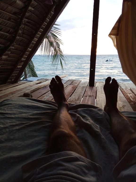 a man laying on a bed looking out at the ocean at Maison typique Madagascar in Anjiabe