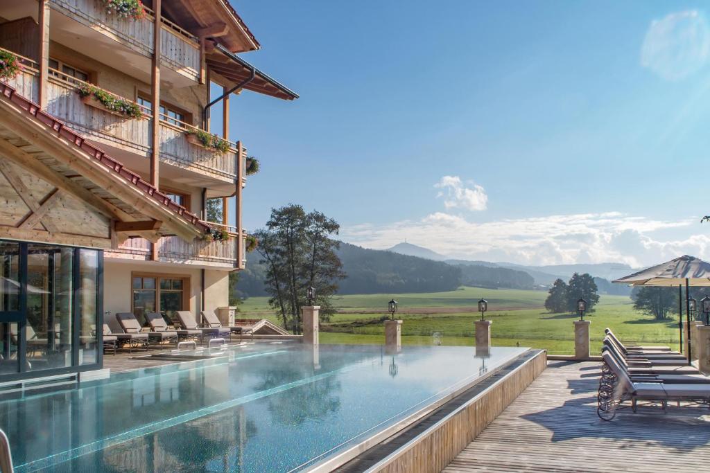 a hotel swimming pool with a view of the mountains at Natur-Wohlfühlhotel Brunner Hof in Arnschwang
