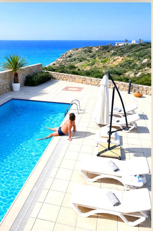 a woman laying in a swimming pool next to the ocean at Golden Sunset Villa in Tatlisu