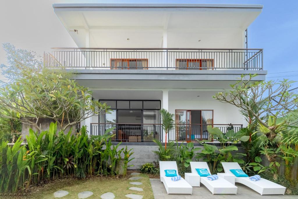 a house with a balcony and chairs in front of it at Casa Lumina Canggu in Canggu