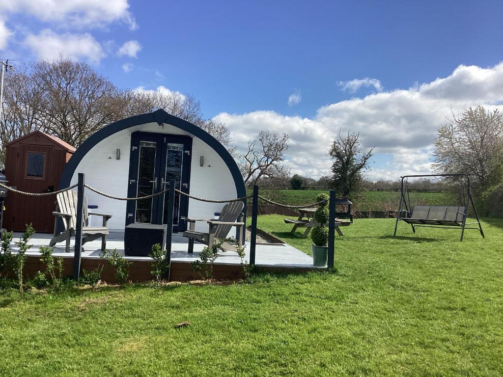 a dome house in a field with chairs and a swing at Cherry Pod 2 in Shrewsbury