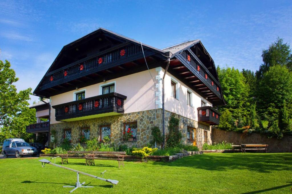 a large building with a gambrel roof with a green yard at Tourist farm Gričnik in Resnik
