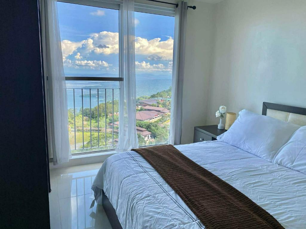 a bedroom with a bed and a large window at Pacific Staycation in Kaybagal