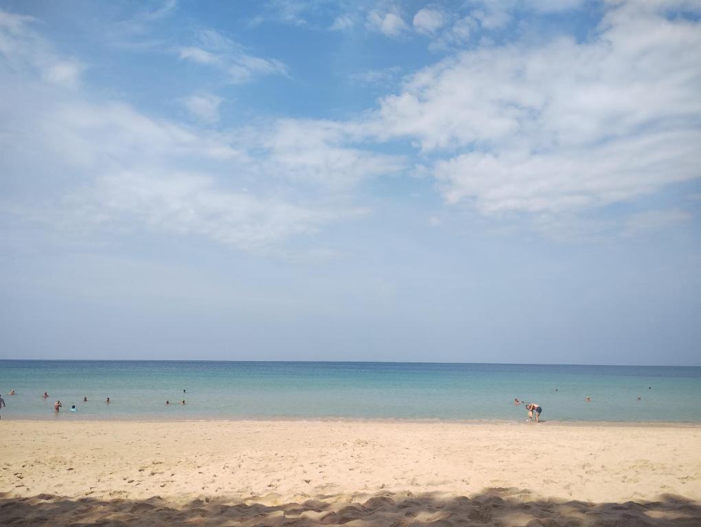 a beach with a lot of people in the water at EnDanni Hostel in Amphoe Thalang