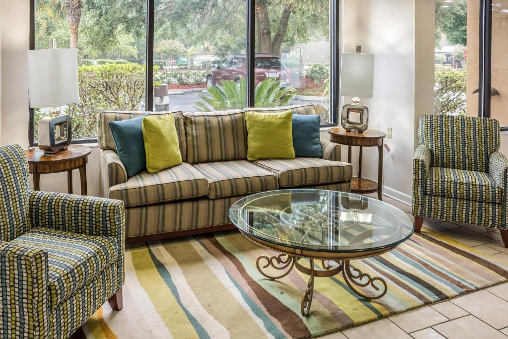 a living room with a couch and two chairs and a glass table at Econo Lodge Palm Coast Central in Palm Coast
