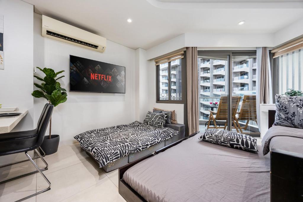 a living room with two beds and a window at Studio for 5 at Tambuli Residences Garden View by Dominik Studio Apartment with Pool Access & Balcony in Mactan in Maribago