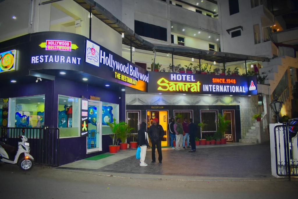 a group of people standing outside of a hotel with a sign at Hotel Samrat International in Mount Ābu