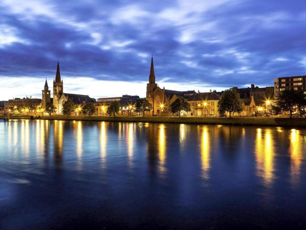 a city lit up at night with a body of water at Mercure Inverness Hotel in Inverness