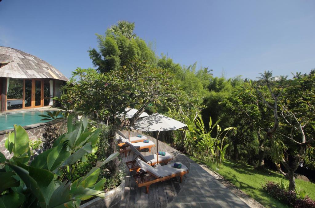 a pool with chairs and an umbrella next to a resort at Babakan Hill Villas in Jasri