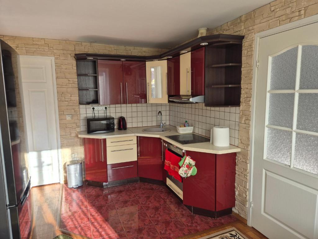 a kitchen with red cabinets and a sink at Mäe Apartment in Tartu