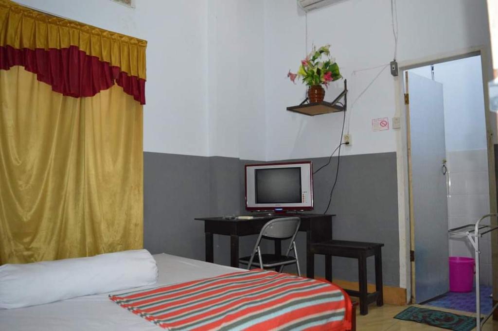a bedroom with a bed and a desk with a television at Hotel SIDAPORE in Lamobuang