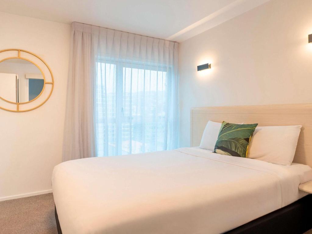 a bedroom with a large white bed and a window at Mantra Central Wellington in Wellington