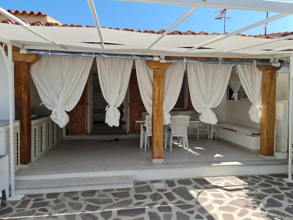 a covered porch with white curtains and a table at Casa Bruna in San Teodoro