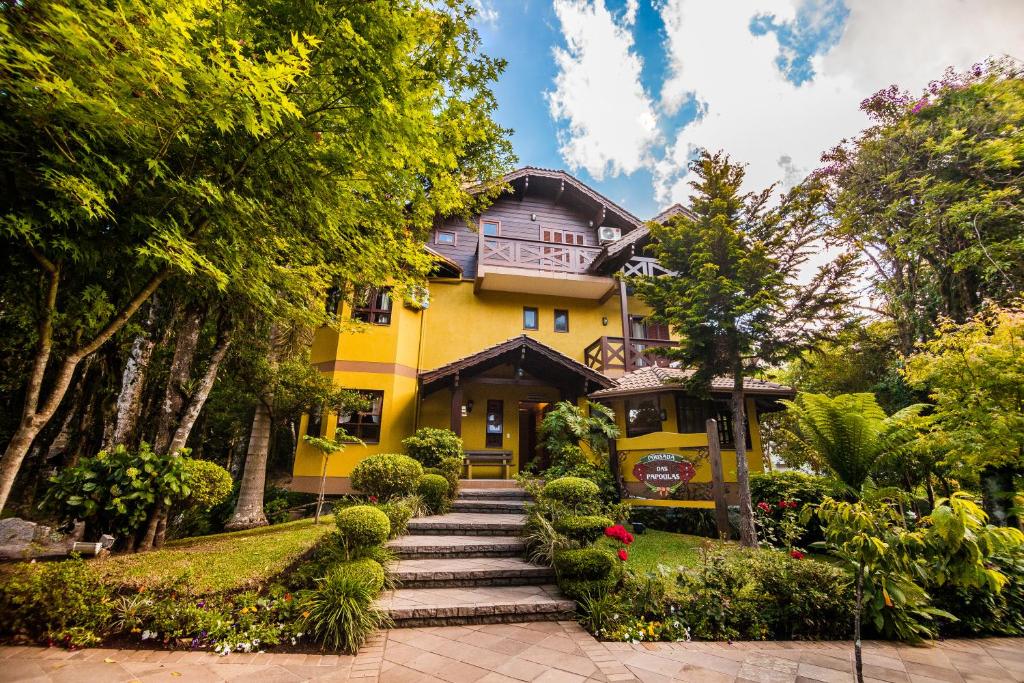 a yellow house with a walkway in front of it at Pousada Das Papoulas in Gramado