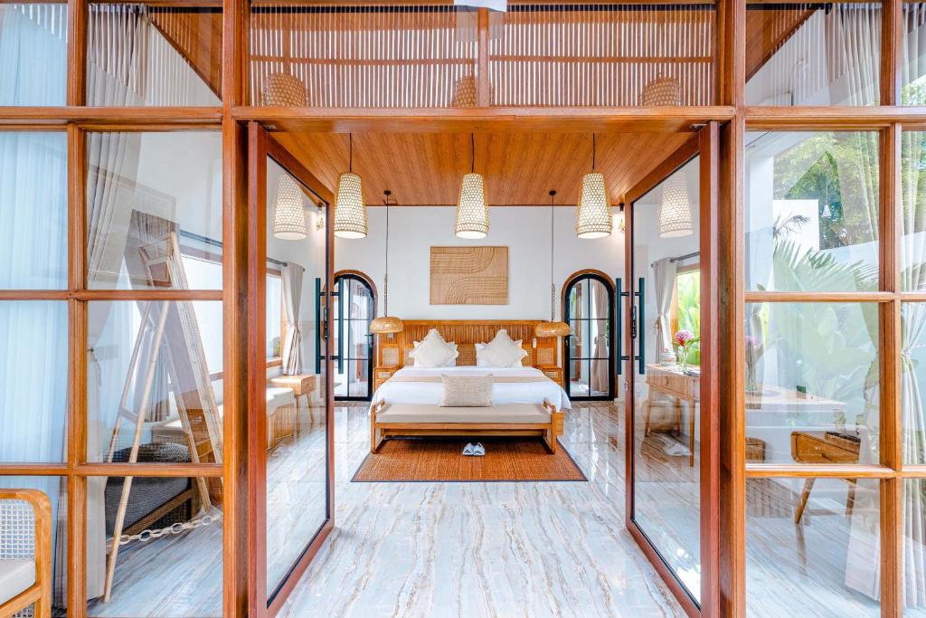 a bedroom with a bed in a room with windows at Sake Bali Suites in Tegalalang