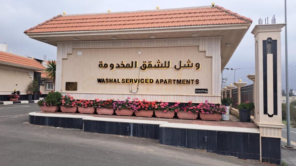 a building with flowers in pots on a street at وشل للشقق المخدومة - اقتصادي Washal Serviced Apartments- standard in Tanomah