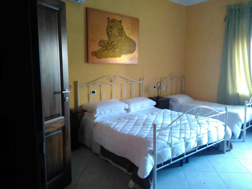 a bedroom with two beds and a cat picture on the wall at Villa Donna Maria in Capoterra