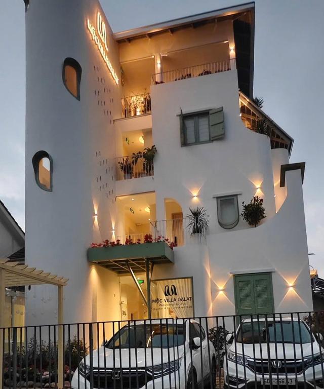 a white building with chairs in front of it at Mộc Villa DaLat in Khu Chi Lăng