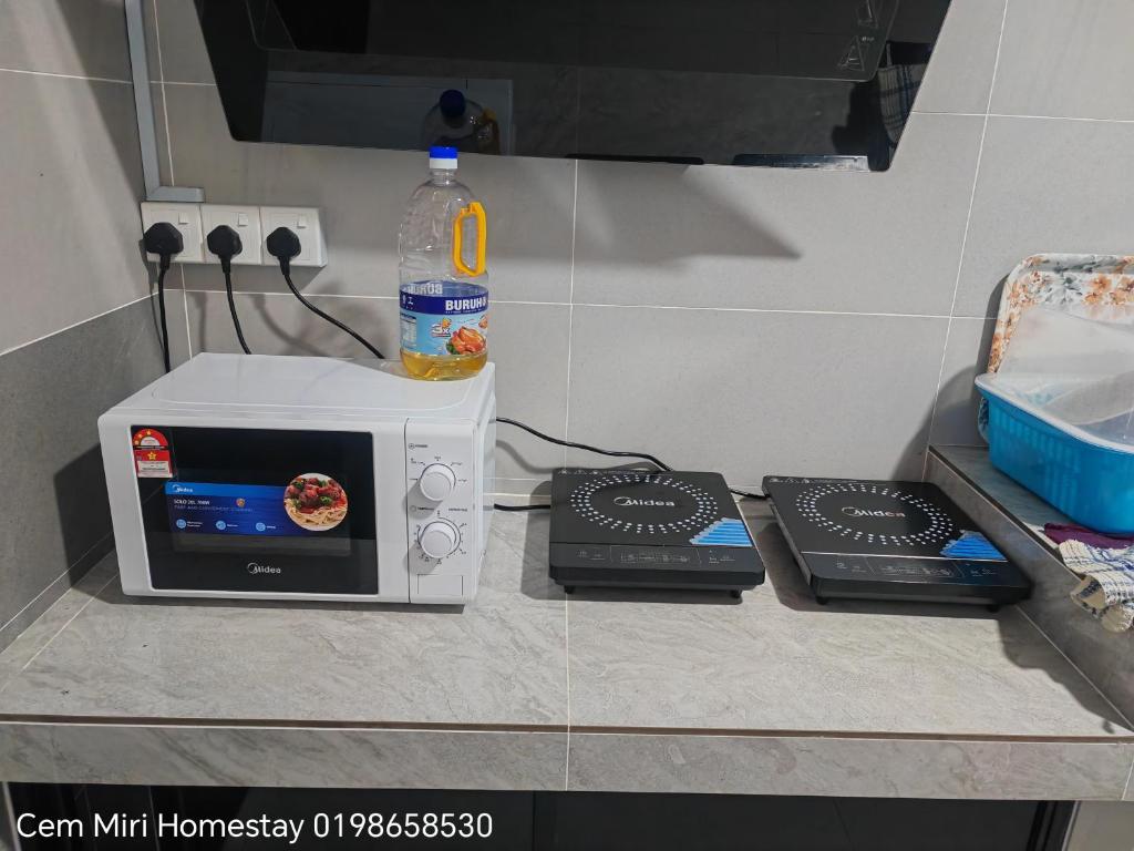 a microwave on a counter with a bottle of water on top at CEM MIRI HOMESTAY in Miri