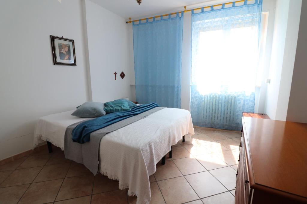 a bedroom with a bed with a blue curtain and a window at Ayra's House Otranto in Otranto