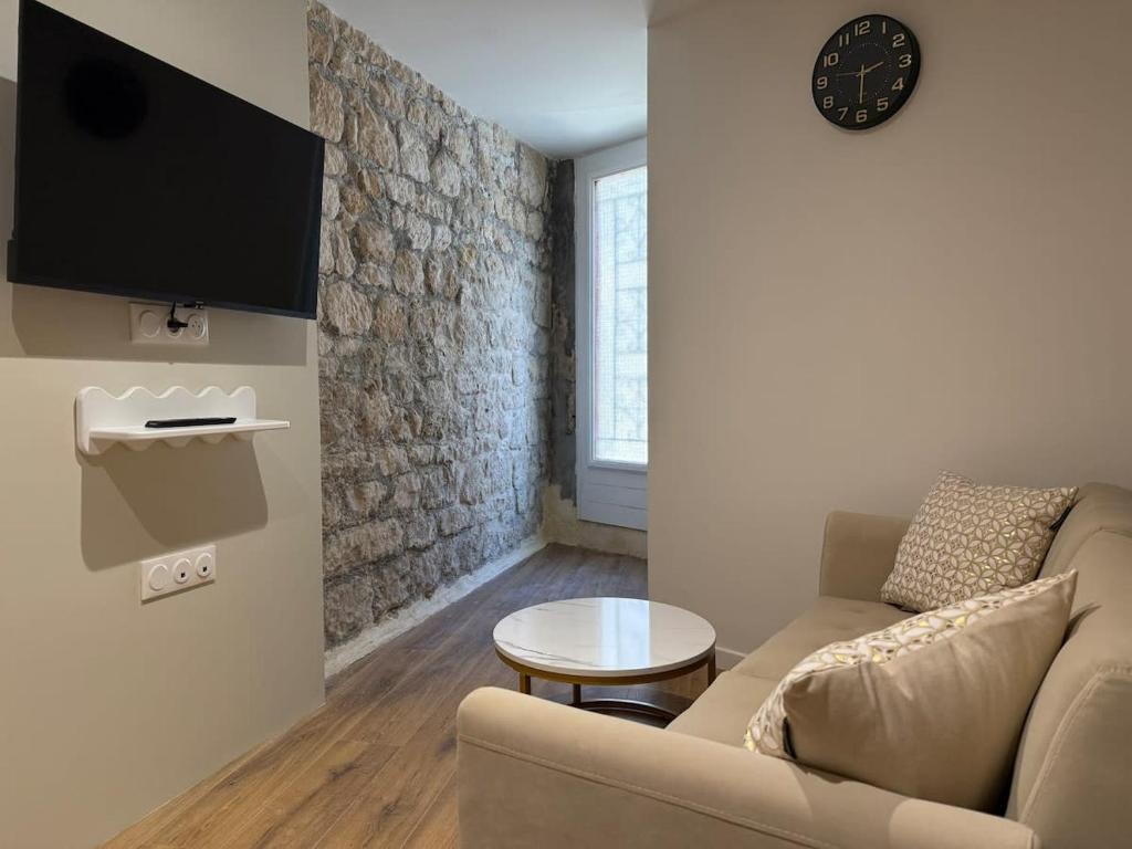 a living room with a couch and a tv on a wall at Le Petit Coin in Saintes