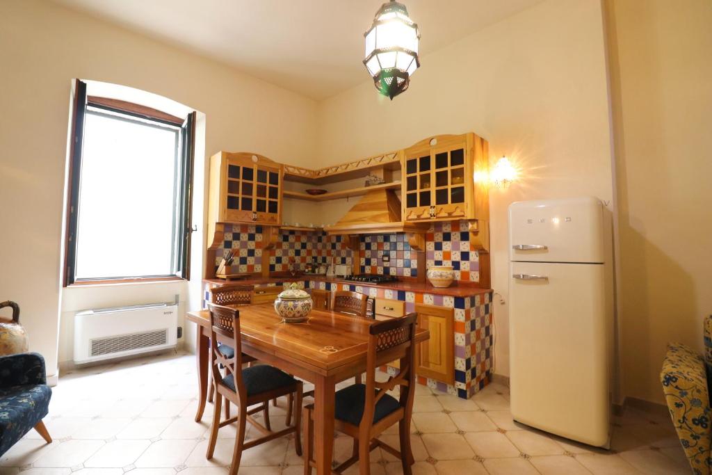 a kitchen with a wooden table and a refrigerator at Dimora Cariddi al Centro Storico in Otranto