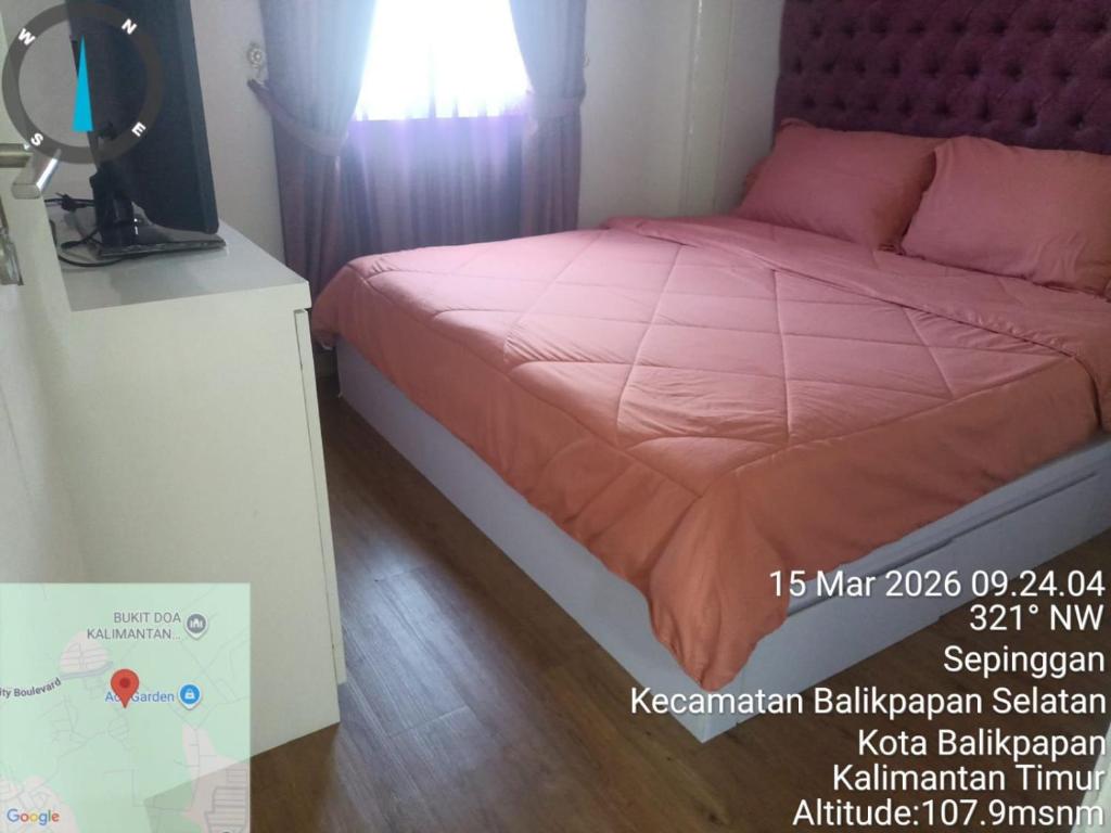a bedroom with a bed with a pink comforter at Villa IDR Grandcity in Balikpapan
