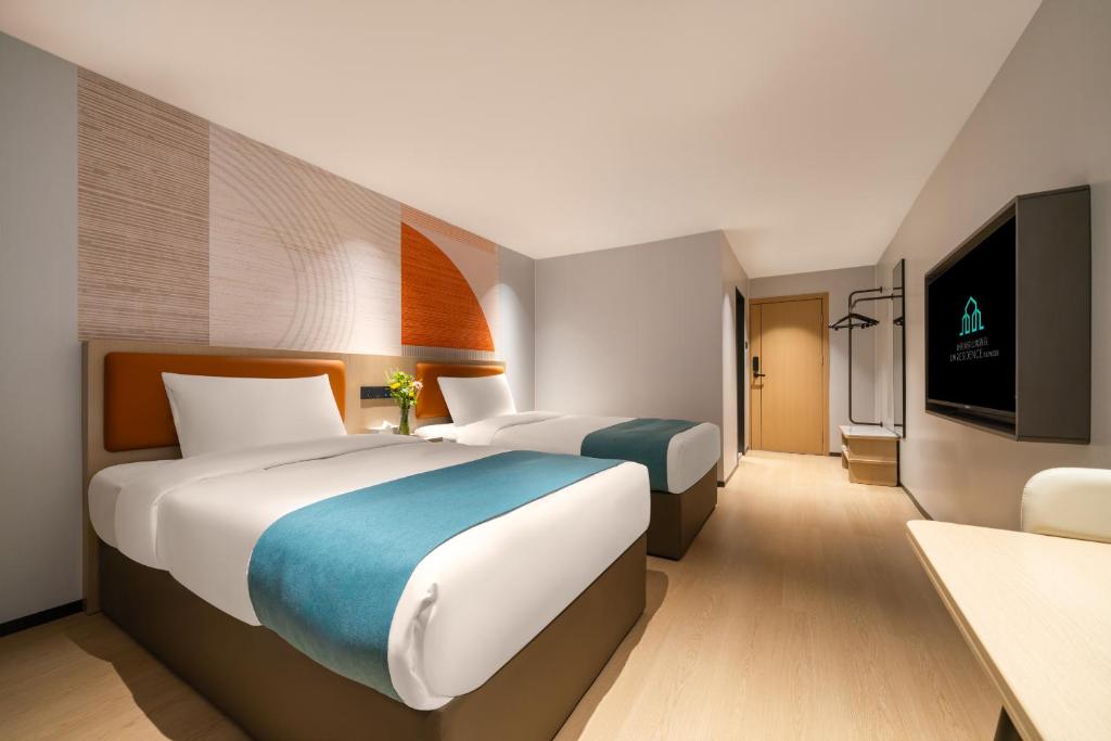 a hotel room with two beds and a flat screen tv at Guang Dong Hotel in Guangzhou