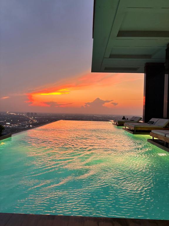 a swimming pool with a sunset in the background at ริเวอร์วิวแม่น้ำเจ้าพระยา62ชั้น in Ban Sai Ma