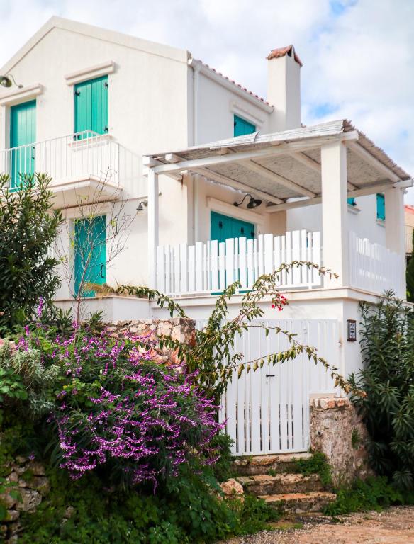 a white house with blue windows and purple flowers at Casa Calypso in Tselendáta